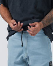Kingz Casual Gi Pant - Light Denim - Close-Up Front View Male Hands Adjusting Drawstring Light Blue Denim Texture Black Label Patch BJJ Gi Training Apparel [color:Light Denim]