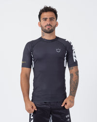Kingz Ranked Performance V2 S/S Rashguard Dark Charcoal White - Full Body Front View Male Athlete Short Sleeve Dark Gray Body White Crown Logo Chest KINGZ Bold White Side Text White Side Panel Gold IBJJF Cuff Matching Shorts BJJ Performance