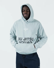 Sea foam green BJJ hoodie front view on adult male model wearing hood up with hands in kangaroo pocket