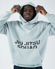 Sea foam green BJJ hoodie lifestyle shot with adult male model pulling drawstring hood over his head