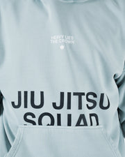 Sea foam green BJJ hoodie front chest closeup of Heavy Lies The Crown logo above Jiu Jitsu Squad print