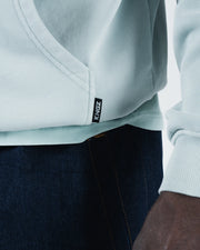 Sea foam green BJJ hoodie hem detail closeup showing woven Kingz label tag and ribbed bottom stitching