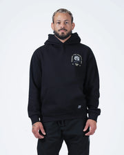 Black BJJ hoodie front view on adult male model showing Pursue The Gentle Art rose chest graphic
