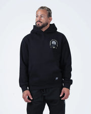 Black BJJ hoodie front three-quarter view on adult male model highlighting rose chest graphic and fit