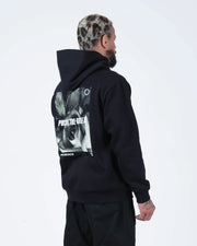 Black BJJ hoodie rear side profile on adult male model showing angled Pursue The Gentle Art rose print