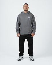Grey BJJ hoodie full body lifestyle shot with adult male model in black joggers and grey sneakers