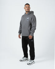 Grey BJJ hoodie full length angled front shot with adult male model in black joggers streetwear styling