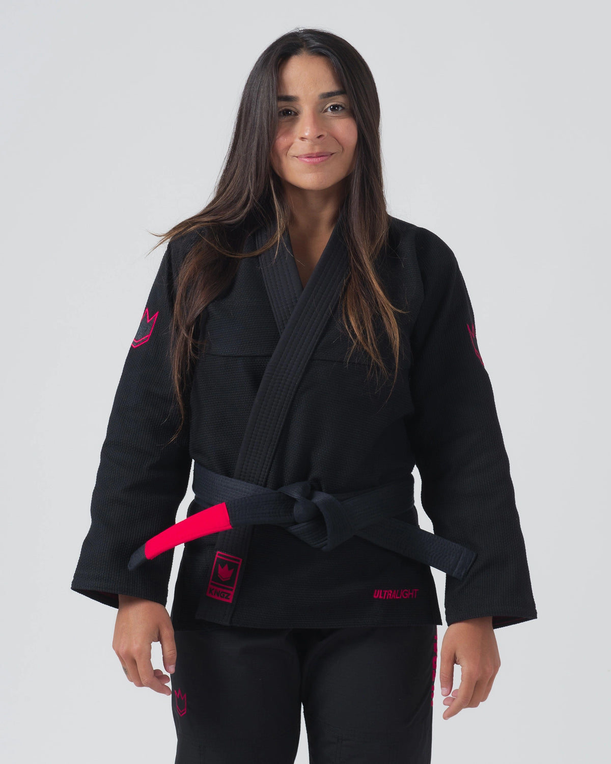 Kingz Ultralight 2.0 Women's Jiu Jitsu Gi Black - Front View Female Athlete Black Gi Pink Crown Embroidery Shoulder Pink Ultralight Text Waist Black Belt Durable Weave BJJ Gi [color:Black]