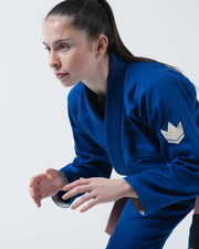Kingz The ONE V2 Women's Jiu Jitsu Gi Blue - Action Side View Female Athlete Blue Gi White Crown Badge Sleeve Reinforced Stitching BJJ Gi Training [color:Blue]