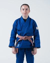 Kingz The ONE V2 Women's Jiu Jitsu Gi Blue - Full Body Front View Female Athlete Blue Gi Crown Badge Left Arm KINGZ Logo Bottom Hem Contrast Stitching Durable Fabric BJJ Gi [color:Blue]
