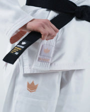 Kingz The ONE V2 Women's Jiu Jitsu Gi White - Close-Up Detail View Hand Holding Black Belt Embroidered Crown Badge Chest and Thigh White Fabric Durable Stitching BJJ Gi [color:White]