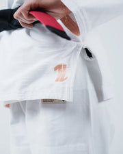 Kingz The ONE V2 Women's Jiu Jitsu Gi - White - Close-Up Detail View Hand Holding Belt Embroidered Logo Side Patch Textured Fabric Premium Crafted Tag BJJ Gi Training [color:White]