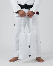 Kingz The ONE V2 BJJ Gi White lower body view holding included crown logo gi bag with black belt above