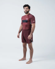 Kingz Trooper Rashguard Maroon - Full Body 3/4 Angled Front View Male Athlete Barefoot Short Sleeve KINGZ Logo Black Chest Band Flag Patches Maroon Shorts