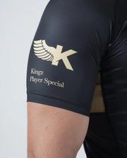 Kingz Player Special Limited Edition Rashguard Black - Close-Up Detail View Arm Gold Winged K Logo Kingz Player Special Text Black Short Sleeve Premium Fit BJJ Grappling Rash Guard [color:Black]