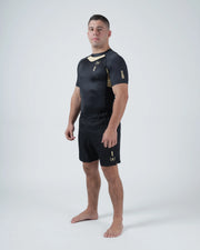 Kingz Player Special Limited Edition Rashguard Black Gold - Full Body 3/4 Angled Front View Barefoot Male Athlete Short Sleeve Gold Chevron Diagonal Panel KINGZ Text Sleeve Shorts [color:Black]