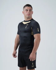 Kingz Player Special Limited Edition Rashguard Black Gold - Full Body Back View Right Side Barefoot Male Athlete Gold Center Back Panel Winged Crown Logo Black Shorts KINGZ Text [color:Black]