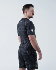 Kingz Acid Wash Rashguard Black - Full Body 3/4 Back View Left Side Male Athlete Short Sleeve Crown Logo Acid Wash Dot Pattern KINGZ Text Shorts Modern Training Gear