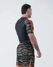 Kingz Always Hunting Rashguard Green Camo - Full Body 3/4 Back View Right Side Male Athlete Short Sleeve Tiger Camo Orange Crown Logo Black Back Panel Camo Shorts Orange Stripe