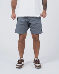 Kingz Casual Gi Shorts Grey Steel Blue-Grey - Full Body Front View Male Athlete Grey Ripstop Casual Shorts Above-Knee Cut Drawstring Waistband Black Woven Kingz Label Right Thigh White T-Shirt Brown Nike Dunk Sneakers Men's BJJ Lifestyle [color:Grey]