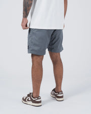 Kingz Casual Gi Shorts Grey Steel Blue-Grey - Full Body Left Side Profile Male Athlete Grey Ripstop Casual Shorts Relaxed Fit Black Woven Kingz Label Right Thigh White T-Shirt Brown Nike Dunk Sneakers Men's BJJ Lifestyle [color:Grey]