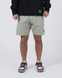 Kingz Casual Gi Shorts Sage Stone Green - Full Body Front View Male Athlete Sage Stone Green Ripstop Casual Shorts Above-Knee Cut Elastic Leg Hem Drawstring Waistband Black Woven Kingz Label Right Thigh Black Hoodie Brown Nike Dunk Sneakers Men's BJJ Lifestyle [color:Stone Green]