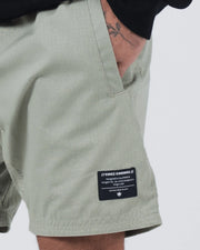 Kingz Casual Gi Shorts Sage Stone Green - Close Up Label Detail KINGZ KIMONOS Woven Label Right Thigh Designed in California Forged for Jiu Jitsu Grapplers Established 2011 Crown Logo Sage Green Ripstop Fabric Texture Men's BJJ Lifestyle [color:Stone Green]