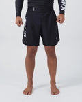 Kingz Kore V2 Shorts Black - Full Body Front View Male Athlete Black Lightweight Grappling Shorts Large KINGZ White Text Left Outer Thigh Crown Logo Right Thigh Elastic Waistband Competition Cut Mid-Thigh Length Black KINGZ Rashguard Bare Feet Men's No-Gi BJJ MMA Kore Collection
