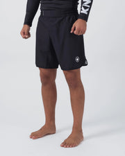 Kingz Kore V2 Shorts Black - Full Body Left Side Profile Male Athlete Black Grappling Shorts Crown Logo White Emblem Right Outer Thigh Elastic Waistband Inner Compression Short Visible Hem Competition Cut Black KINGZ Rashguard Bare Feet Men's No-Gi BJJ MMA Kore Collection