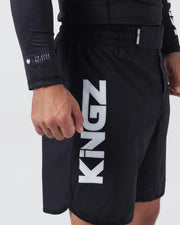 Kingz Kore V2 Shorts Black - Close Up Left Thigh Side View Large KINGZ White Vertical Text Left Outer Thigh KINGZ KIMONOS Elastic Waistband JIU JITSU ROYALTY Crown Patch Sleeve Black Lightweight Grappling Fabric Men's No-Gi BJJ MMA Kore Collection