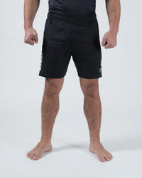 Kingz Player Special Limited Edition Shorts Black Gold - Full Body Front View Male Athlete All-Black KINGZ Gold Text Left Leg Gold Crown Badge Right Thigh Black Elastic Waistband Competition Cut Men's Grappling Shorts No-Gi BJJ Tainan Dalpra Signature Collection [color:Black]