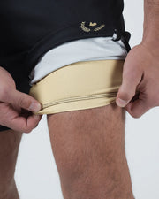 Kingz Player Special Limited Edition Shorts Black - Close-Up Detail View Hands Adjusting Hem Gold Inner Lining Black Outer Layer Gold Laurel Crown Badge Waist Grappling Shorts BJJ No-Gi [color:Black]