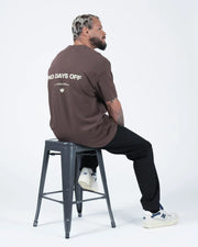 Kingz No Days Off Tee - Seated Lifestyle Back View - No Days Off Print Mocha Brown BJJ Casual Tee Stool