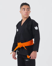Kingz Kore V2 Youth BJJ Gi Black - Upper Body 3/4 Angled Side View Teen Athlete Orange Belt Crown Logo Sleeve Youth