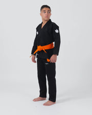 Kingz Kore V2 Youth BJJ Gi Black - Full Body Angled Front View Teen Athlete Orange Belt Crown Logo Sleeve Youth Kids