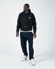 Black BJJ hoodie full length angled walking shot with adult male model showing casual streetwear styling