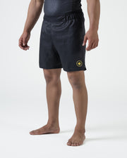 Kingz MI-K Roots Onça Pintada Shorts Black - Full Body Right Side Profile Male Athlete Dark Charcoal Black Gold MI-K Circular Crown Badge Right Thigh Competition Cut Men's Grappling Shorts No-Gi BJJ MI-K Roots Jaguar