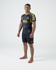 Kingz MI-K Roots Onça Pintada Rashguard Midnight Gray - Upper Body 3/4 Front View Male Athlete Short Sleeve BRASIL Gold Text Brazil Flag Crown Logo Gold Side Panel KINGZ Text Limited Edition