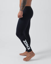 Kingz Kore Grappling Spats Black - Full Body Left Side Profile Shirtless Tattooed Male Athlete All-Black KINGZ Large Bold White Vertical Text Right Calf Full-Length Compression Fit Men's No-Gi BJJ Spats Kore Collection